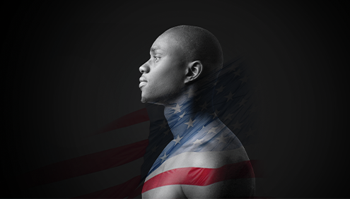 Black background with a profile photo of a strong young black man with bare skin from the chest up in the center. The man's expression shows neither joy, nor sorrow. This photo is overlayed with a transparent American flag in mid wave wrapping across the man's neck and chest.