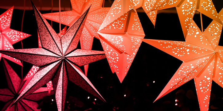 Festive red, orange, and yellow paper stars with intricate cut outs are hung in anticipation of an exciting holiday event.